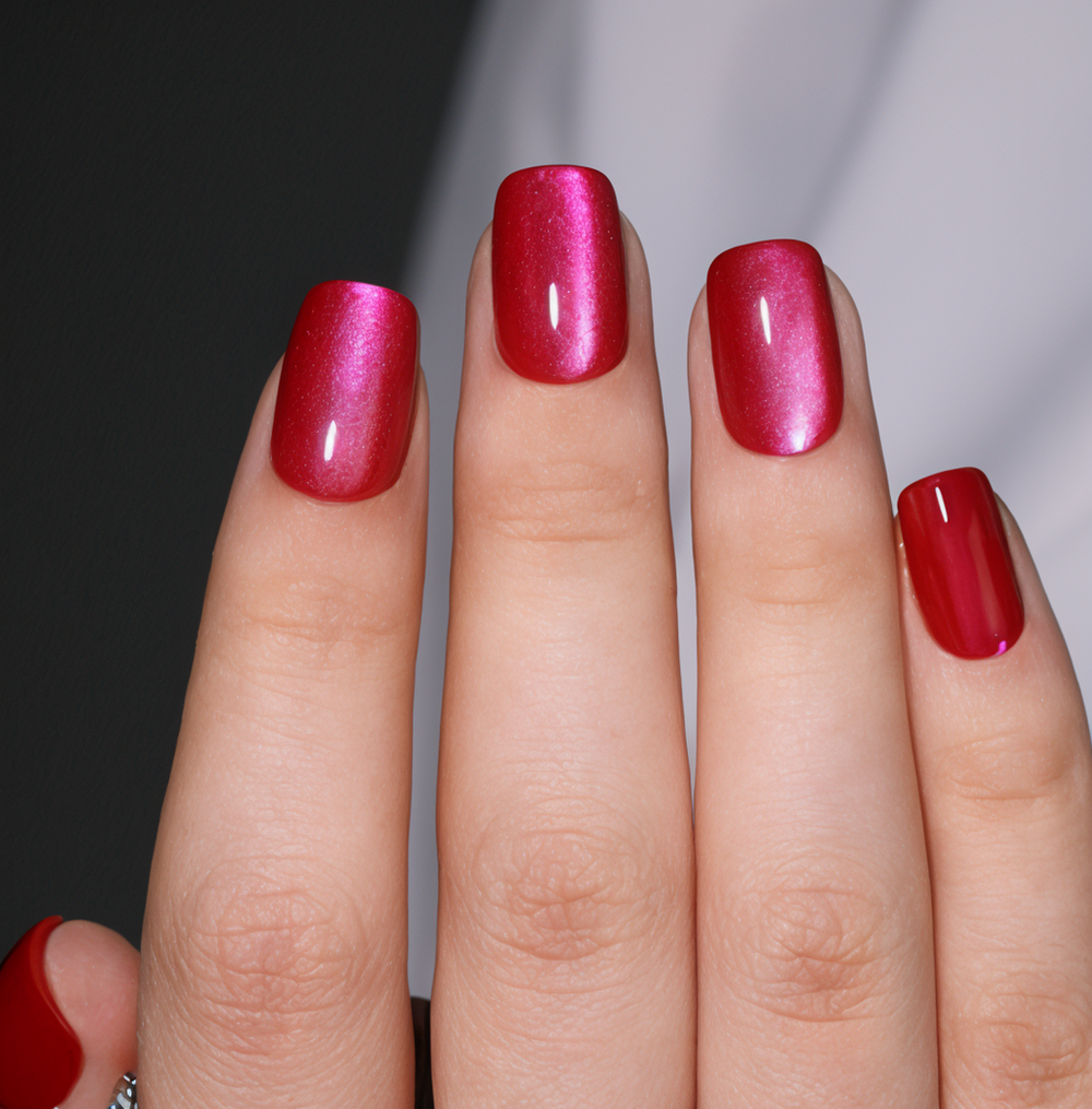 Close-up of a hand with red nail polish on a neutral background